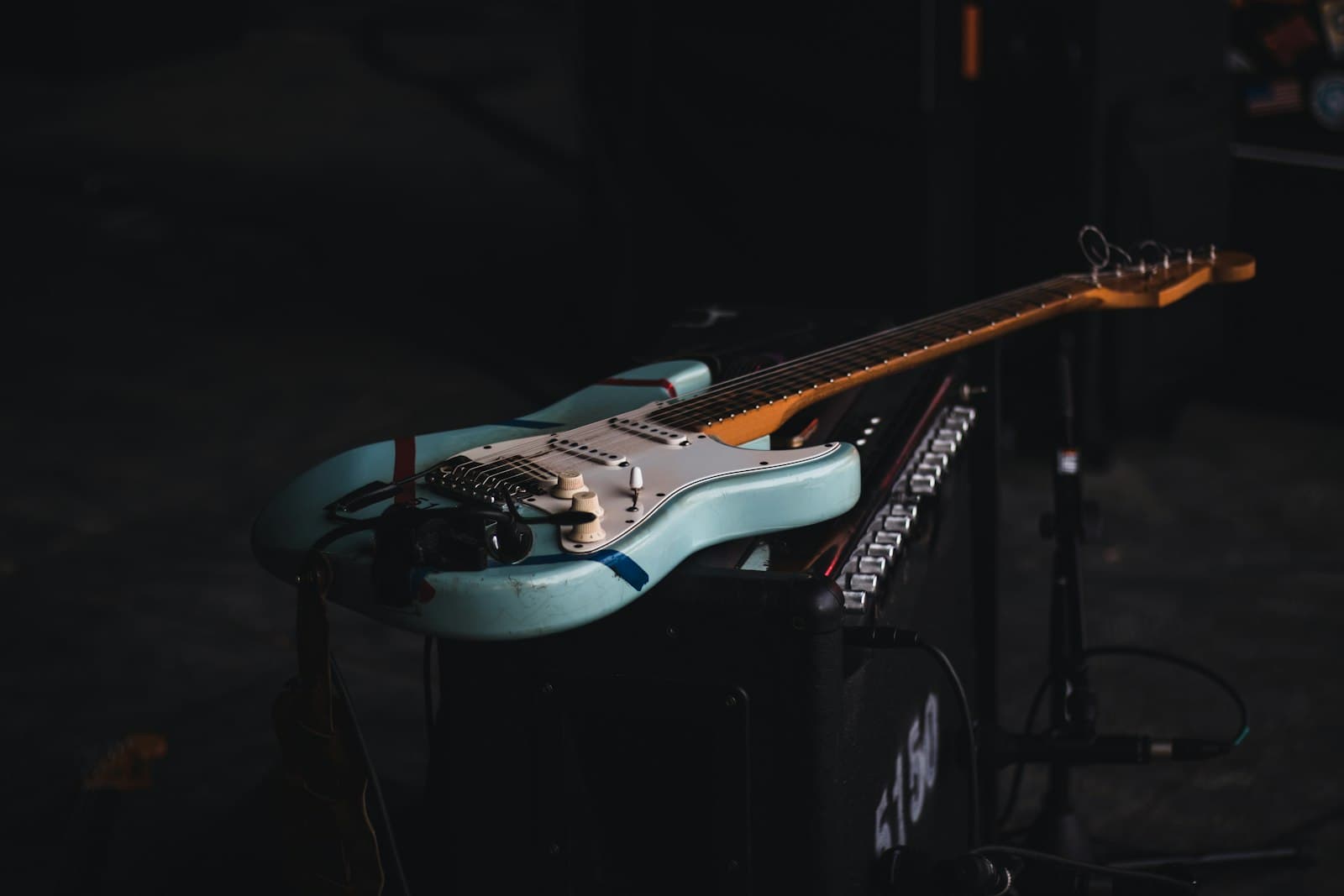 An electric guitar resting on an amp in the dark